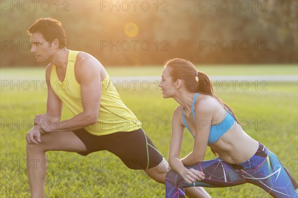 Couple stretching legs in field