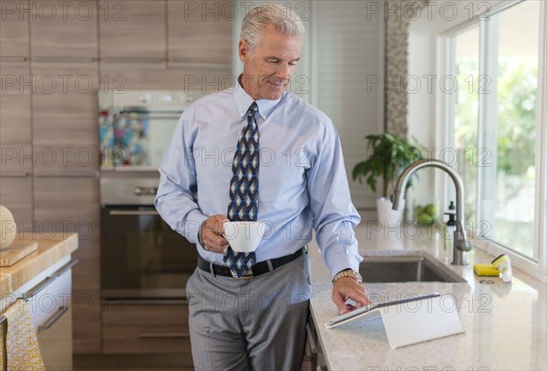 Caucasian businessman using digital tablet in kitchen