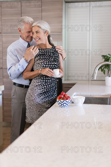 Caucasian couple hugging in kitchen