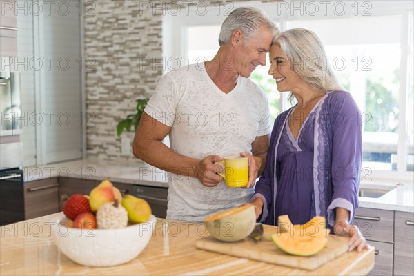 Caucasian couple touching foreheads in kitchen