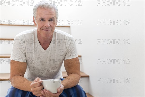 Caucasian man drinking coffee on stairs