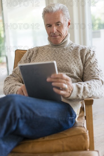 Caucasian man using digital tablet in armchair