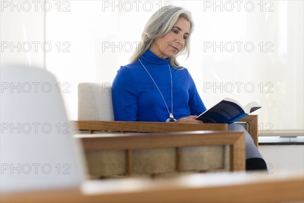 Caucasian woman reading book in armchair