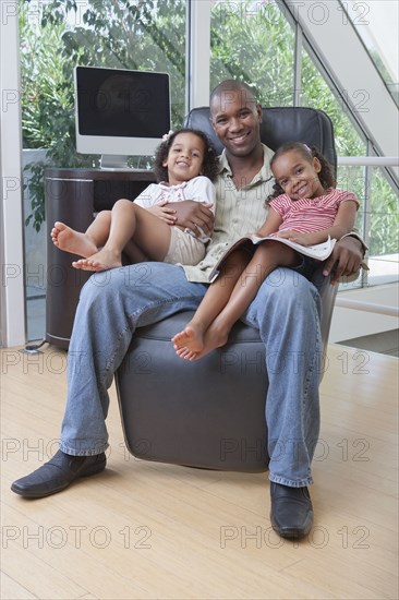 African American father holding daughters on his lap