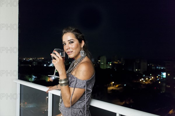 Woman drinking wine on urban balcony