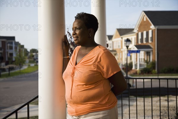 Pensive African woman standing on front stoop of house