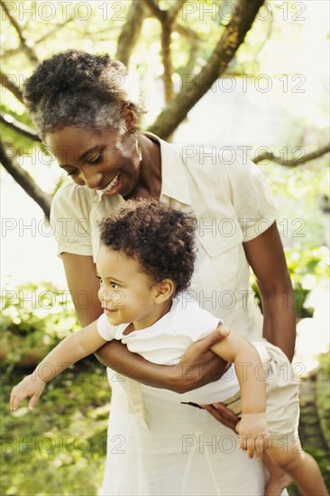 African woman playing with son outdoors