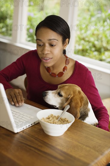 African woman with dog looking at laptop