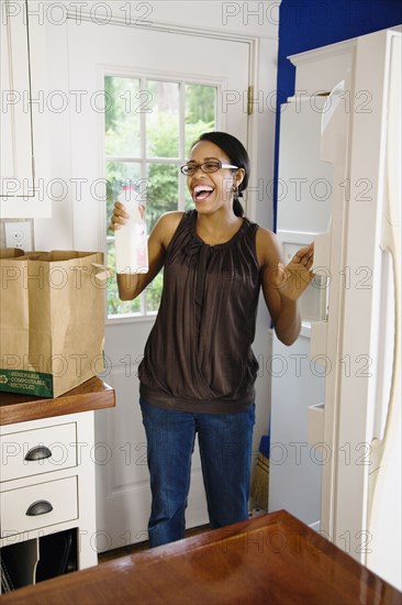 African woman unloading groceries in kitchen