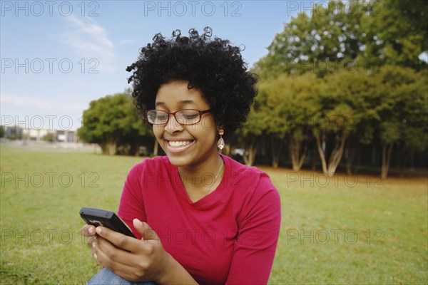 Mixed race woman text messaging on cell phone