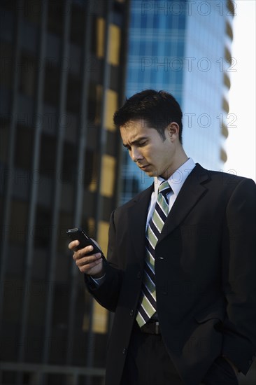 Mixed race businessman text messaging on cell phone