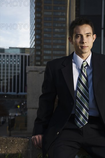 Mixed race businessman sitting on urban rooftop