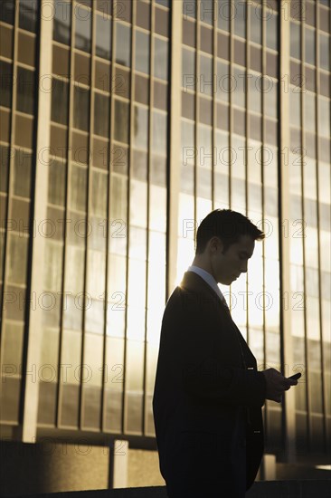 Mixed race businessman text messaging on cell phone