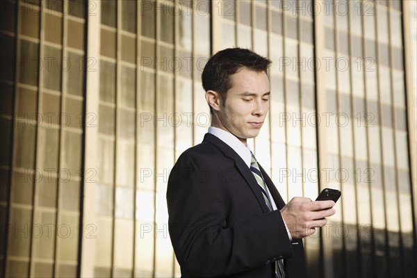 Mixed race businessman text messaging on cell phone