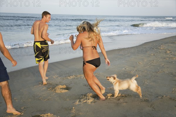 Teenagers and puppy running on beach