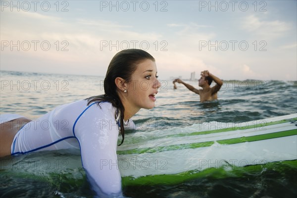 Caucasian teenage girl paddling on surfboard in ocean