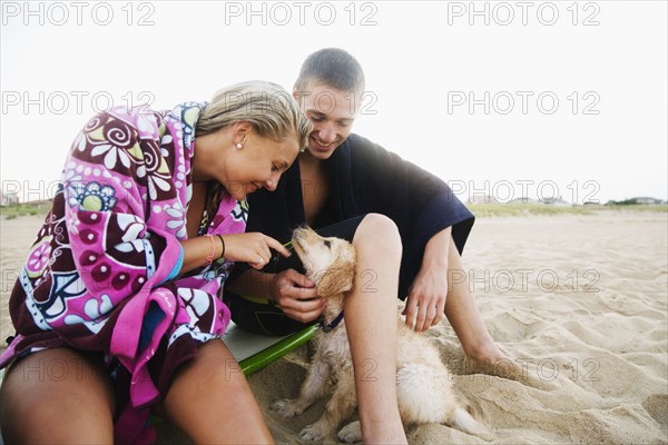 Teenage couple with puppy on beach