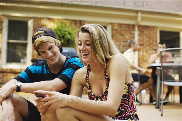 Couple hanging out together on patio looking at cell phone