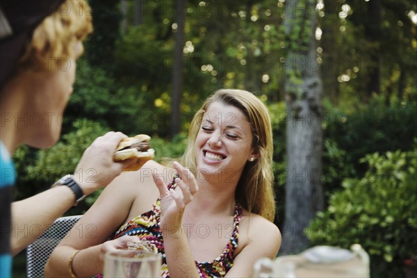 Teenage boy teasing girlfriend with hamburger