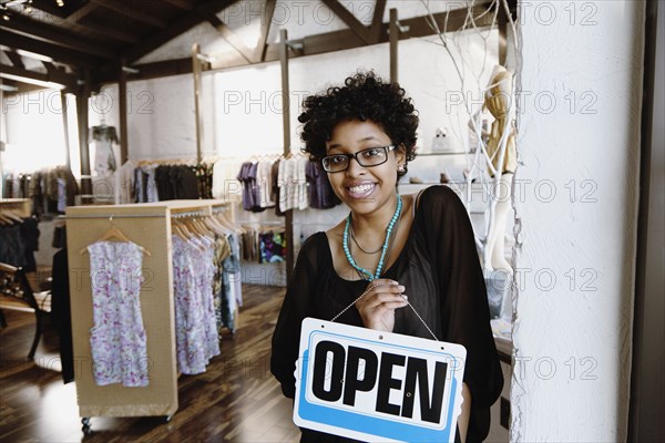 Mixed race woman putting open sign on door