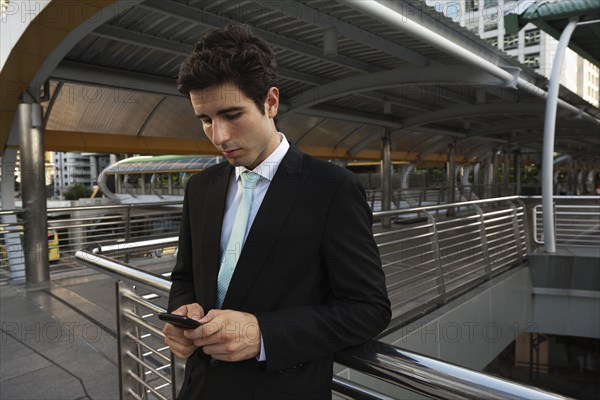 Caucasian businessman text messaging on cell phone outdoors