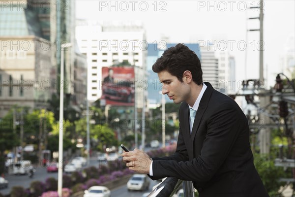 Caucasian businessman text messaging on cell phone outdoors