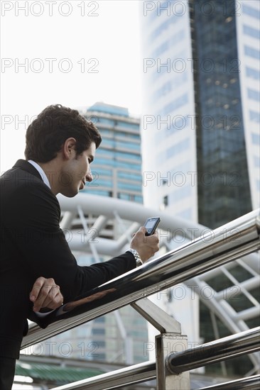 Caucasian businessman text messaging on cell phone outdoors