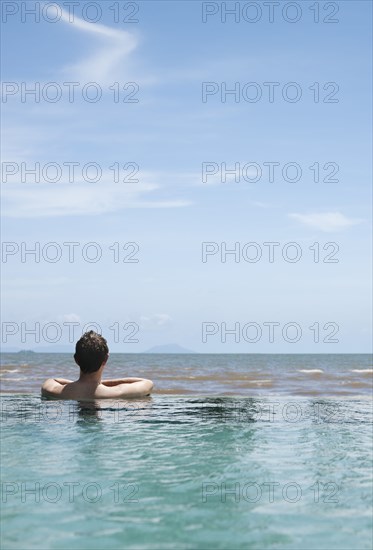 Caucasian man swimming in infinity pool