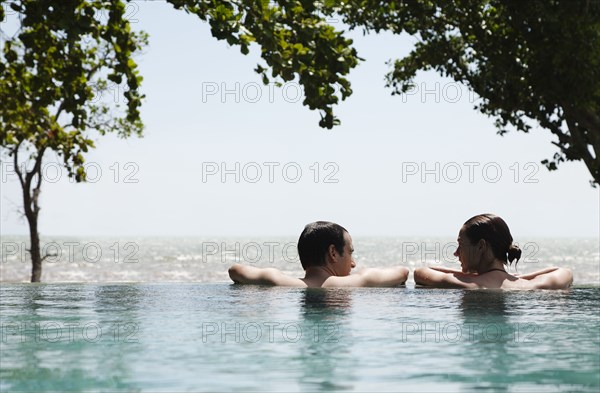 Caucasian couple swimming in infinity pool together