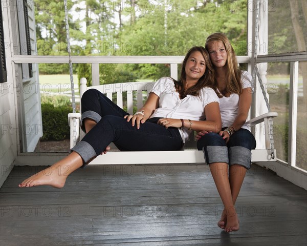 Caucasian sisters sitting on porch swing together