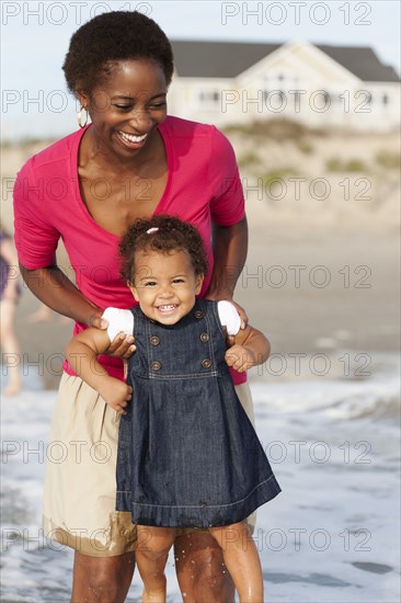 Smiling mother playing with daughter on beach