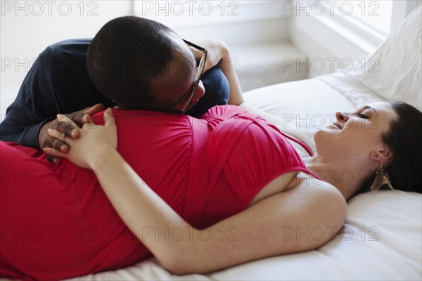 Husband laying on bed with pregnant wife