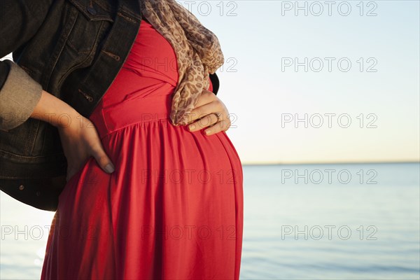 Pregnant Caucasian woman standing near ocean
