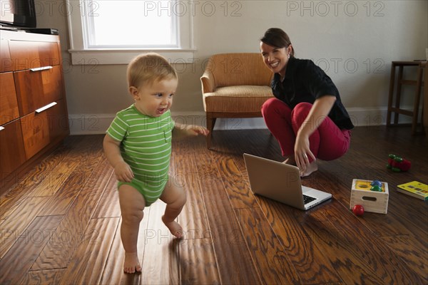 Caucasian mother watching toddler son walk