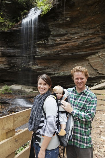 Caucasian family smiling by waterfall