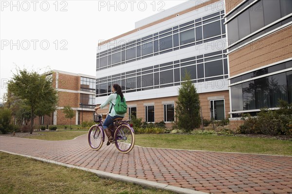 Caucasian student riding bicycle on campus