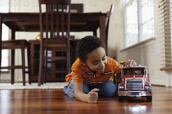 Mixed race boy playing with fire truck on floor