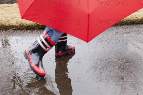 Mixed race boy splashing in rainboots