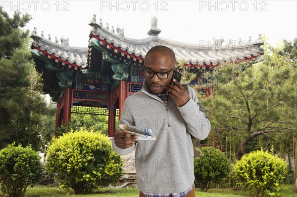 Black man reading map on city street