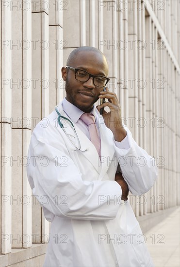 Black doctor talking on cell phone on city street