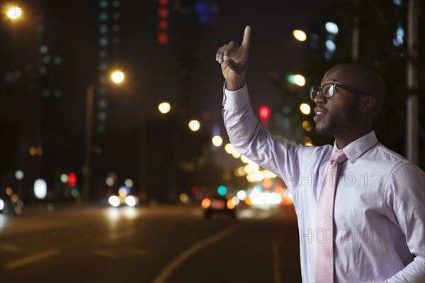 Black businessman hailing taxi on city street