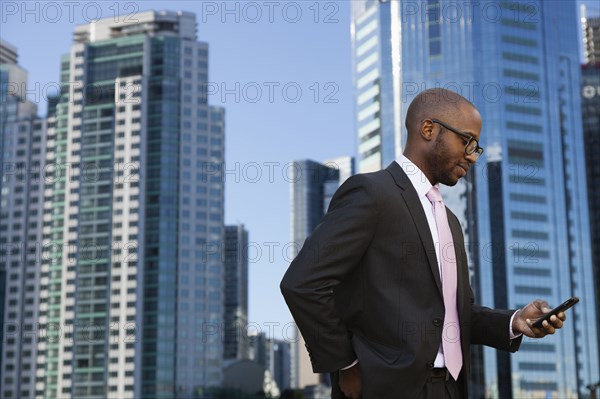 Black businessman using cell phone on city street