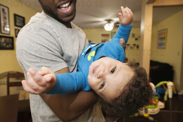 Father playing with baby in living room