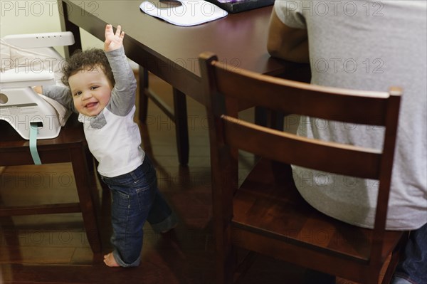 Baby climbing into high chair at table