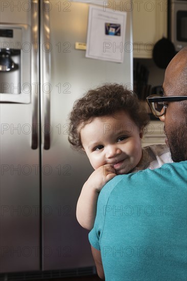 Father holding baby in kitchen