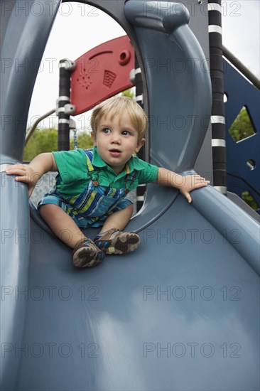 Caucasian boy playing on slide