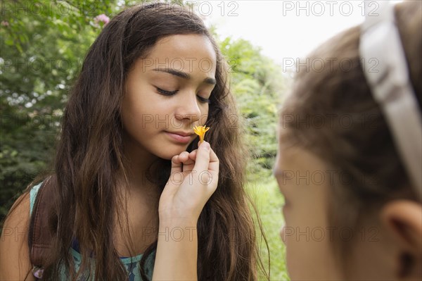 Mixed race girls smelling flowers