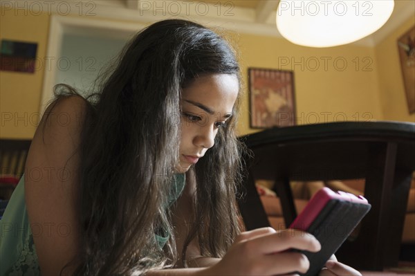 Mixed race girl using digital tablet on floor