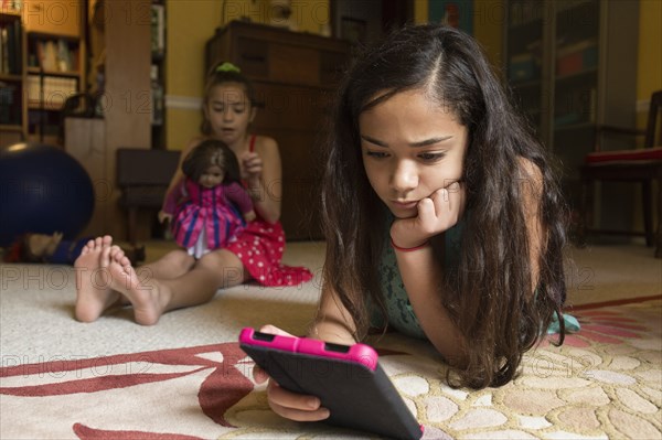 Mixed race girl using digital tablet on floor