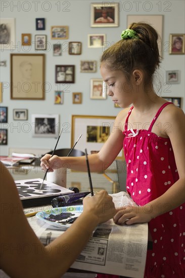 Mixed race mother and daughter painting sign